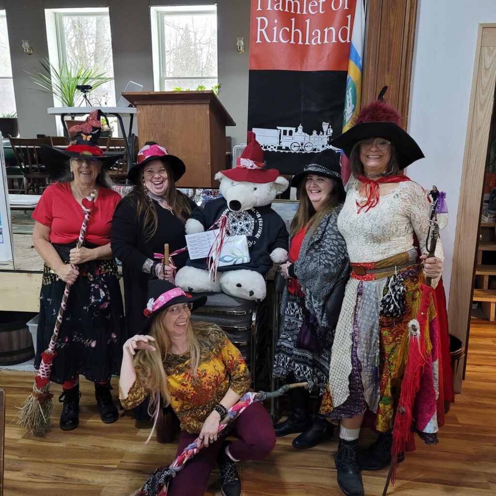 women dressed as witches with brooms and stuffed bear