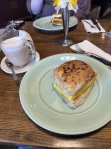 A breakfast sandwich and mug of tea on a wooden table